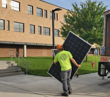 person carrying solar panel to Edina school