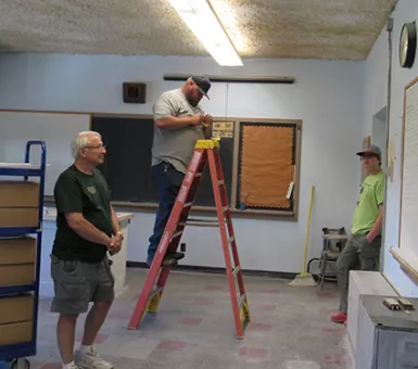 People installing lights in old classroom