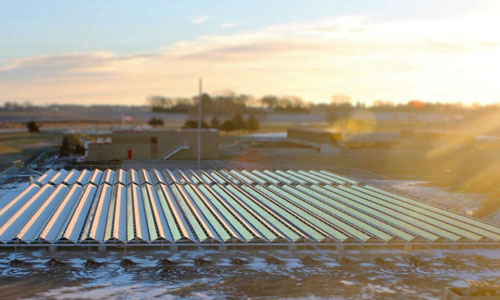The sun rises over Hutchinson’s new solar PV project, the largest on a landfill in Minnesota, and the first ballast-mounted on a brownfield. Hutchinson’s wastewater treatment facility, the recipient of the array’s electricity, can be seen in the background